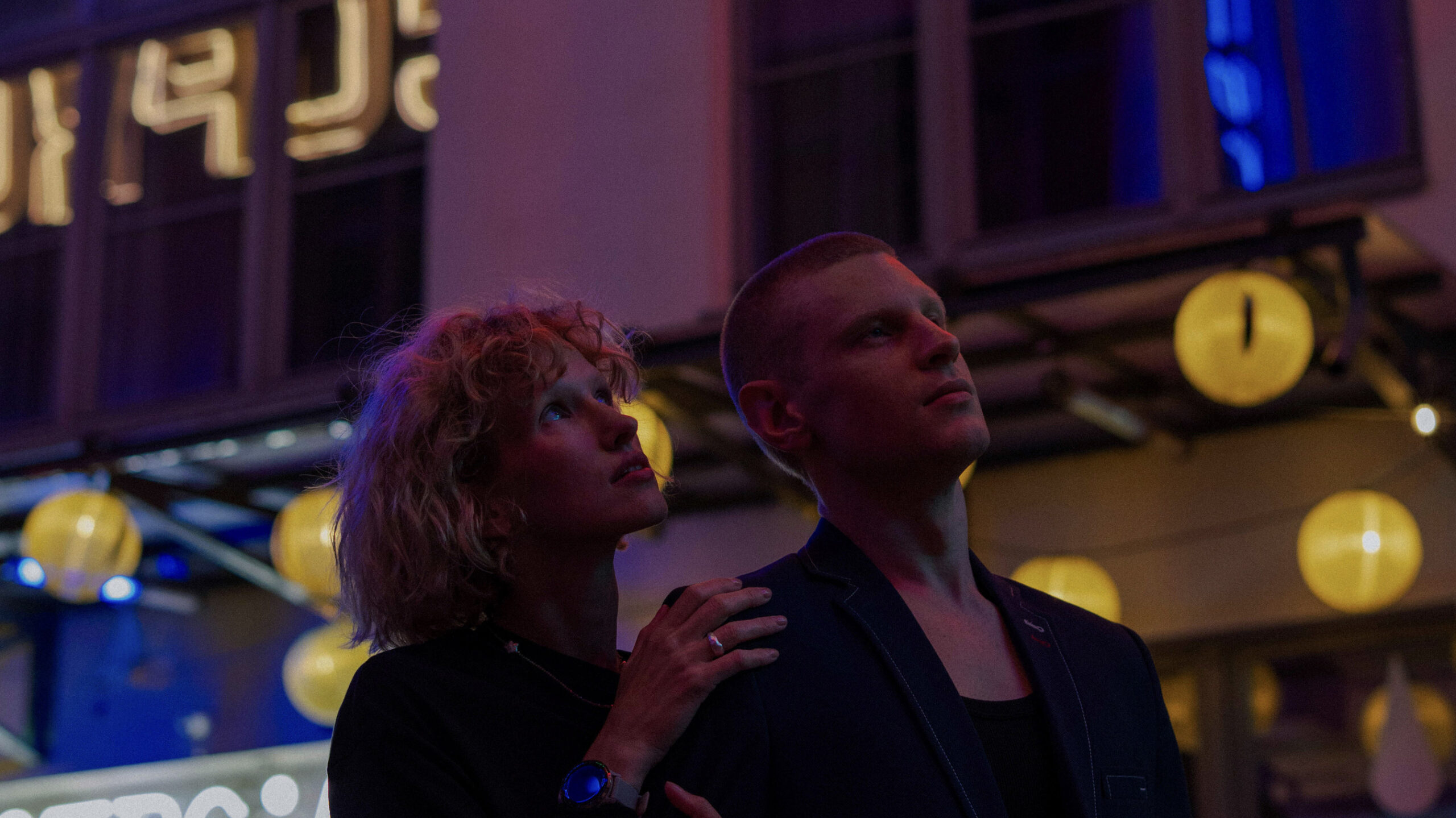 Kobieta i mężczyzna podczas wieczornego spaceru podziwiają nocne życie Wrocławia rozświetlone neonami.
